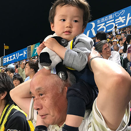 田舎から阪神ファンのおじいちゃんが出て来て祖父母と一緒に野球を見に行きました。途中疲れてきたぼくをおじいちゃんが肩車してくれて、よく見えるようになって少し怖々ですが嬉しそう。最後まで寝ずに観戦しました。